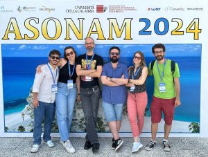 A bunch of nerds posing in front of the asonam conference logo